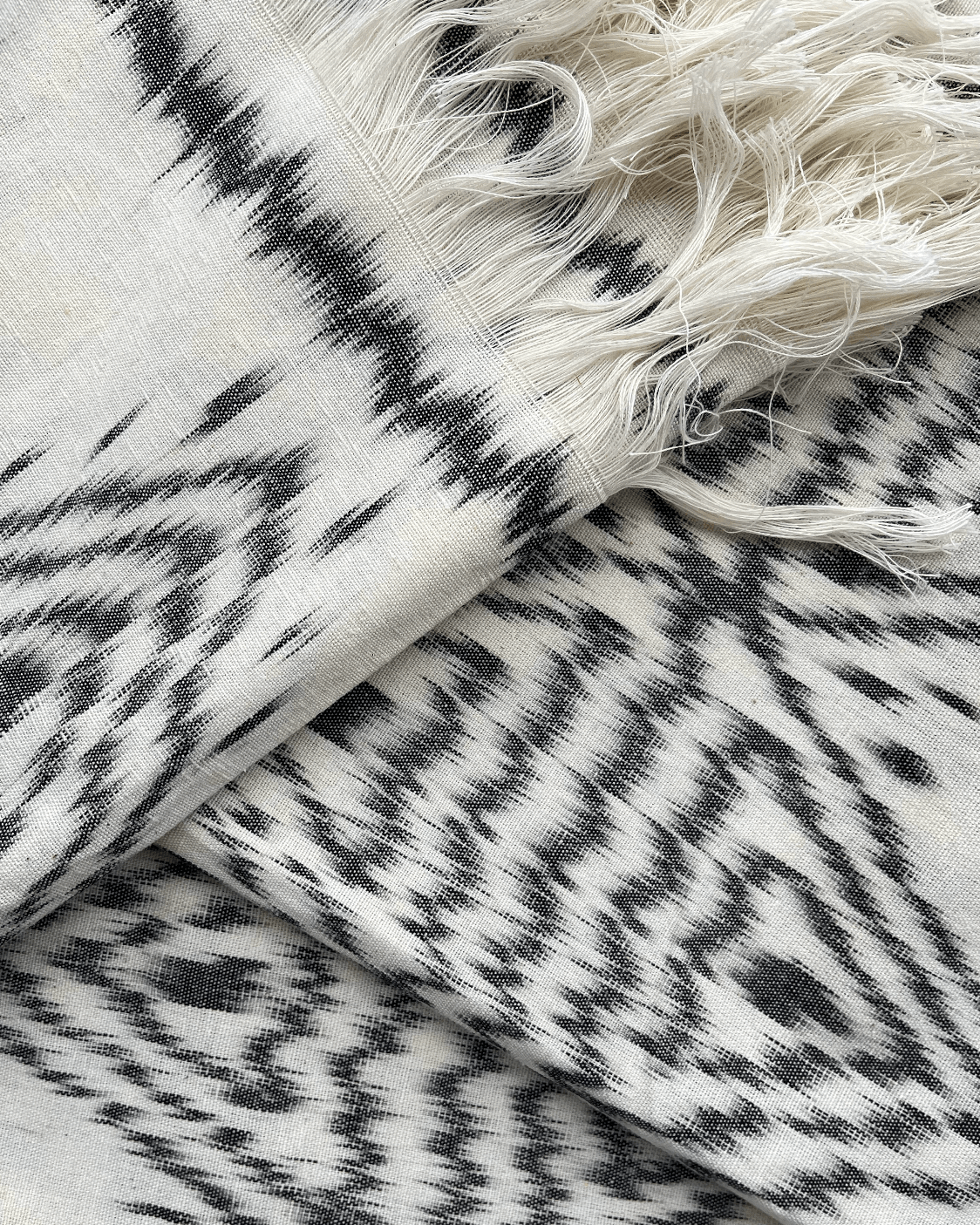 Rękodzielnicza tkanina ikat z czarno-białym geometrycznym wzorem. Unikalna tkanina wykonana tradycyjną techniką ikat idealnie wpisuje się w trendy rękodzieła i sztuki użytkowej. 